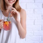 A young woman enjoys a flavored moonshine drink from Tennessee Shine Co. out of mason jar glass