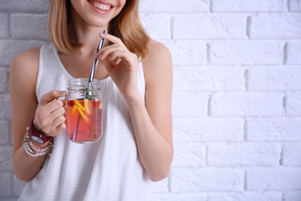 A young woman enjoys a flavored moonshine drink from Tennessee Shine Co. out of mason jar glass